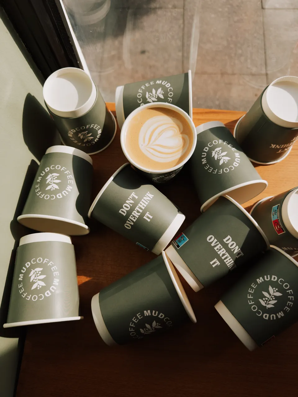 Cappuccino și paharele verzi MUD la fereastră